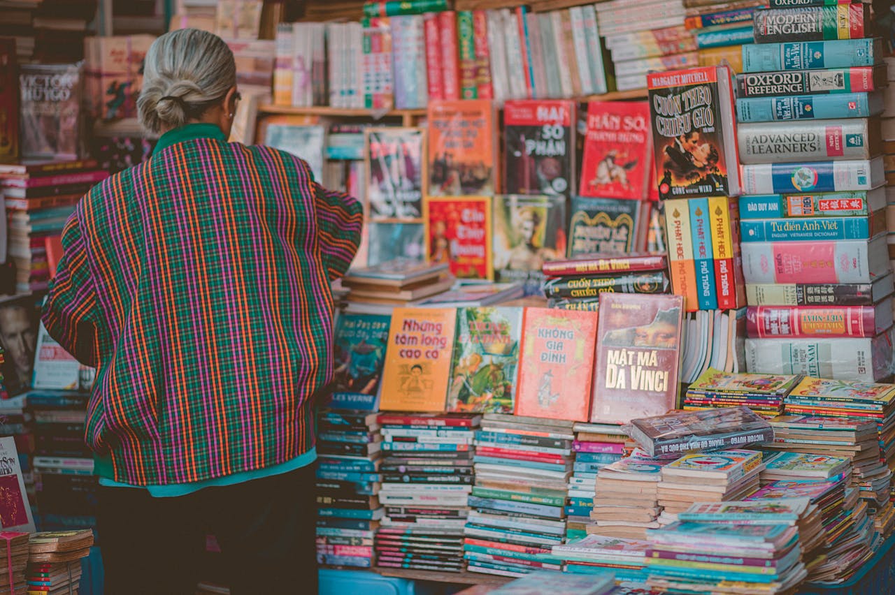 A senior woman in colorful attire browsing a diverse book display in a bookstore.